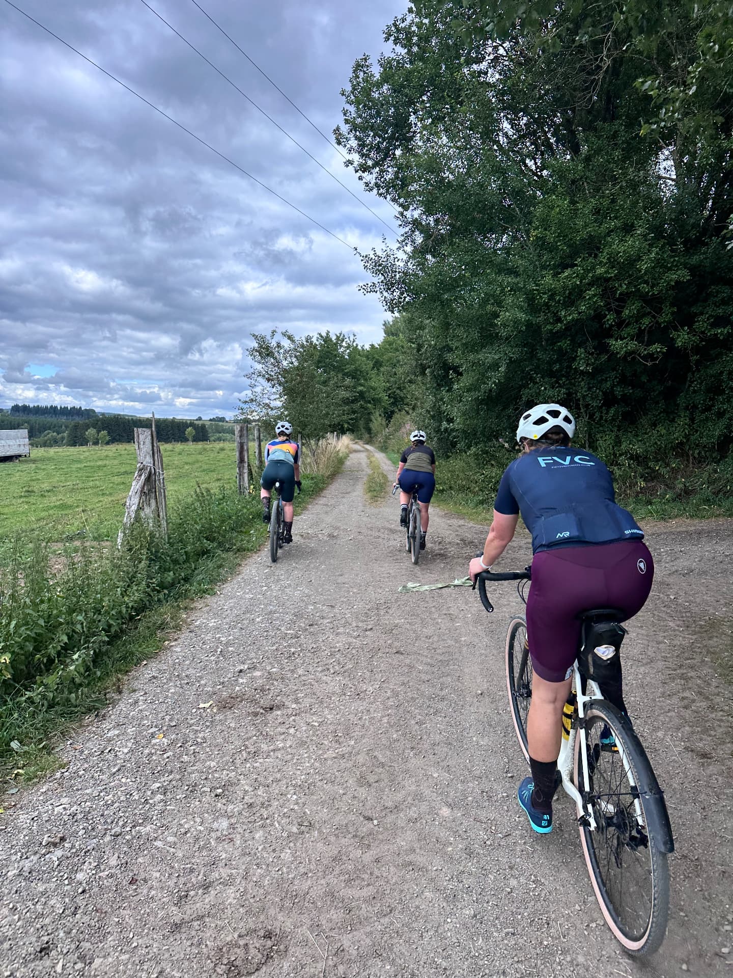Sfeer van een eerdere Fietsvrouwen-rit in de Ardennen: de groep fietst over een gravelpad tussen weilanden en bos