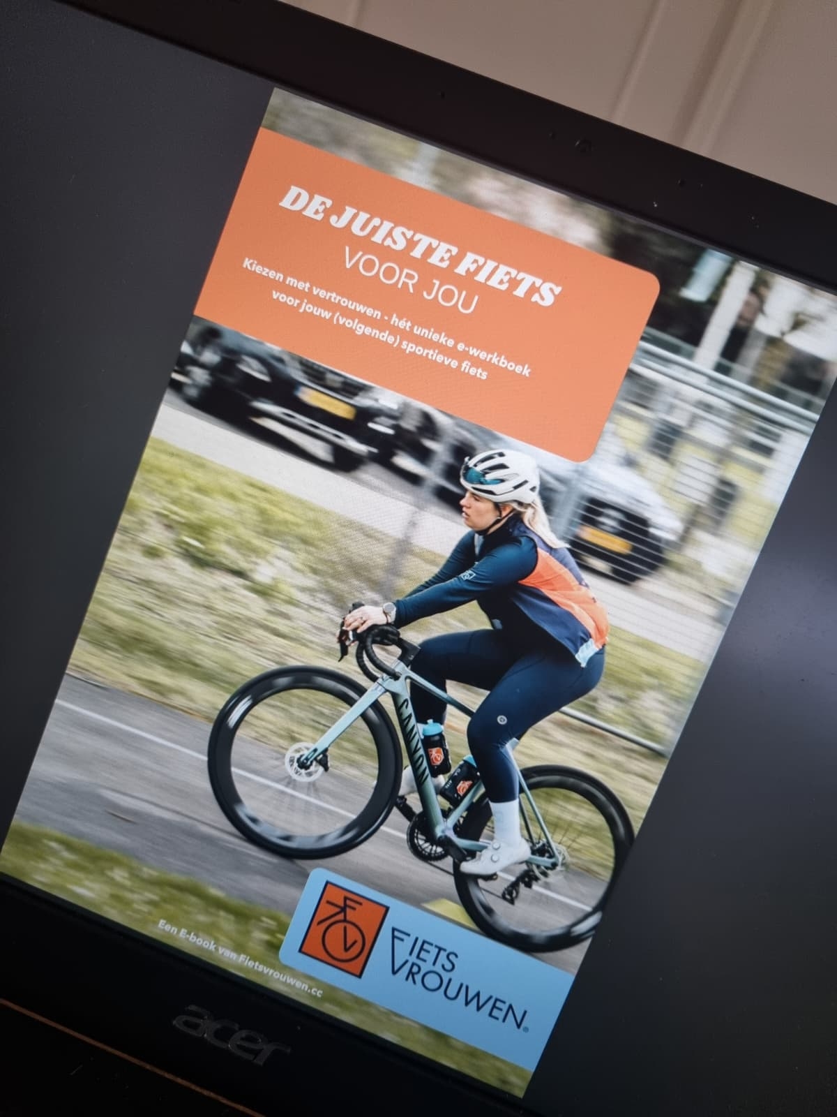Omslag van het Fietsvrouwen e-book De juiste fiets voor jou op een laptopscherm, met een wielrenster op een racefiets