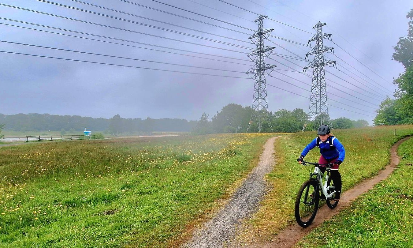 Mountainbiker op een graspad langs hoogspanningsmasten bij de TT-baan in Assen