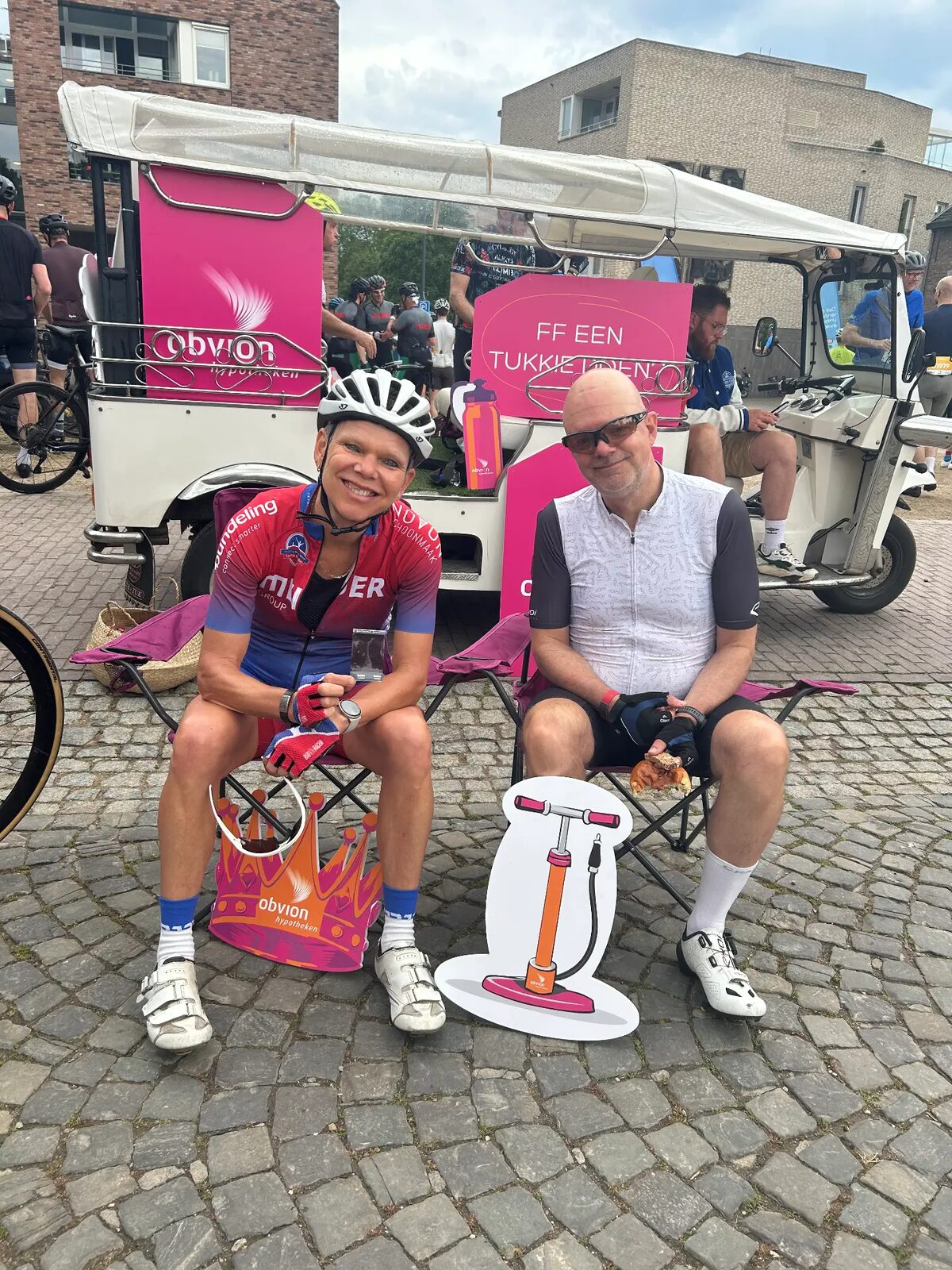 Twee fietsers rusten uit op stoeltjes tijdens Limburgs Mooiste in Zuid-Limburg