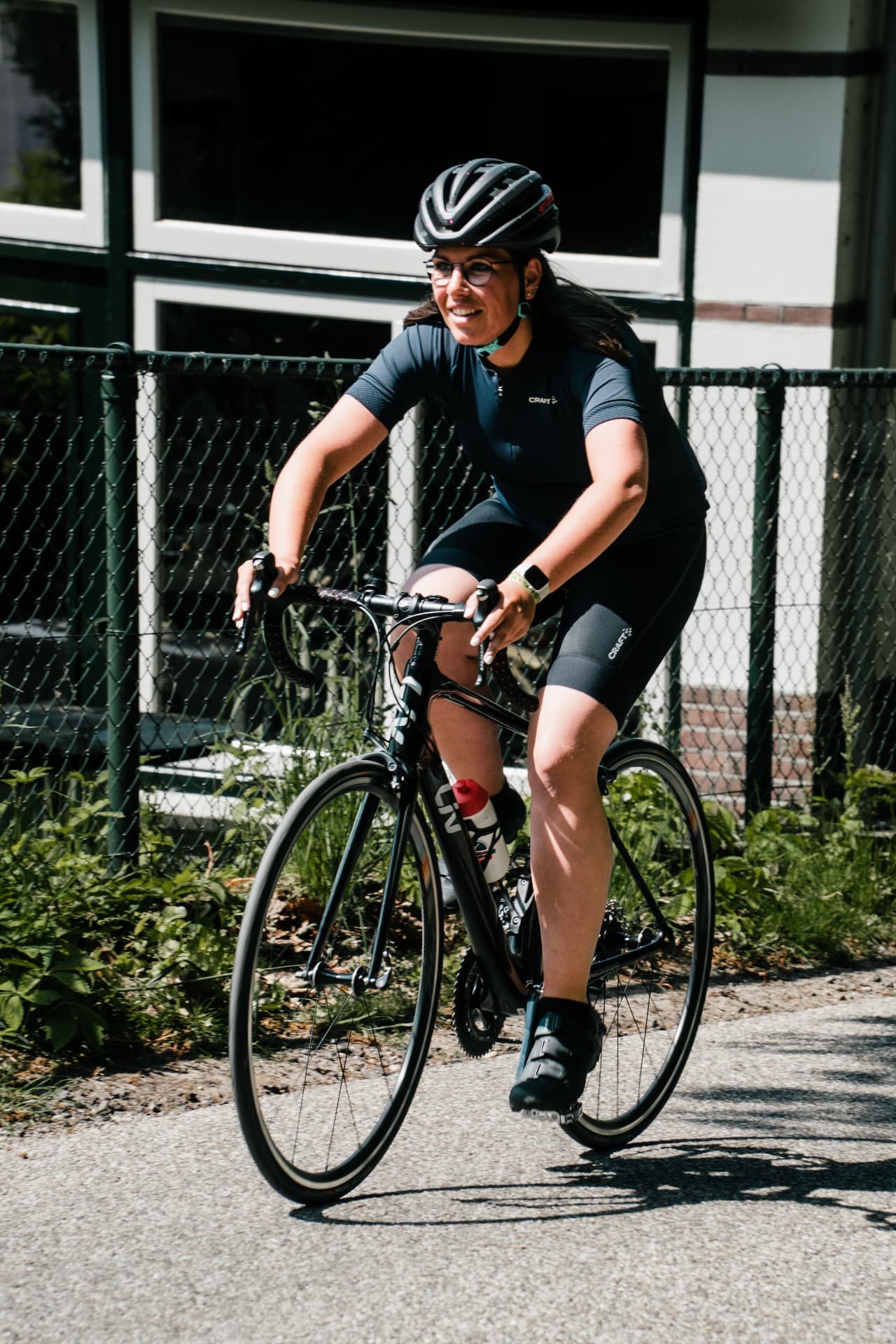 Lachende deelneemster op haar racefiets tijdens een clubrit in Nijverdal