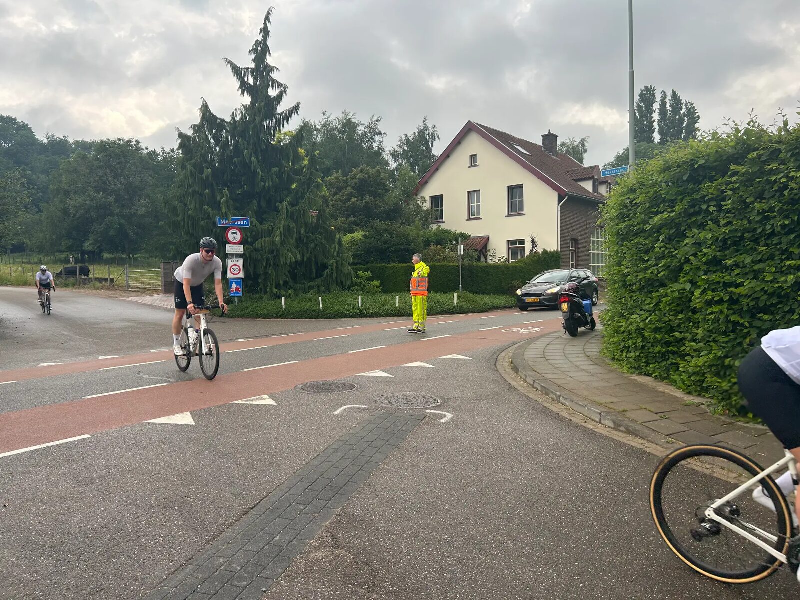 Verkeersregelaar bij een kruising tijdens Limburgs Mooiste terwijl racefietsers passeren