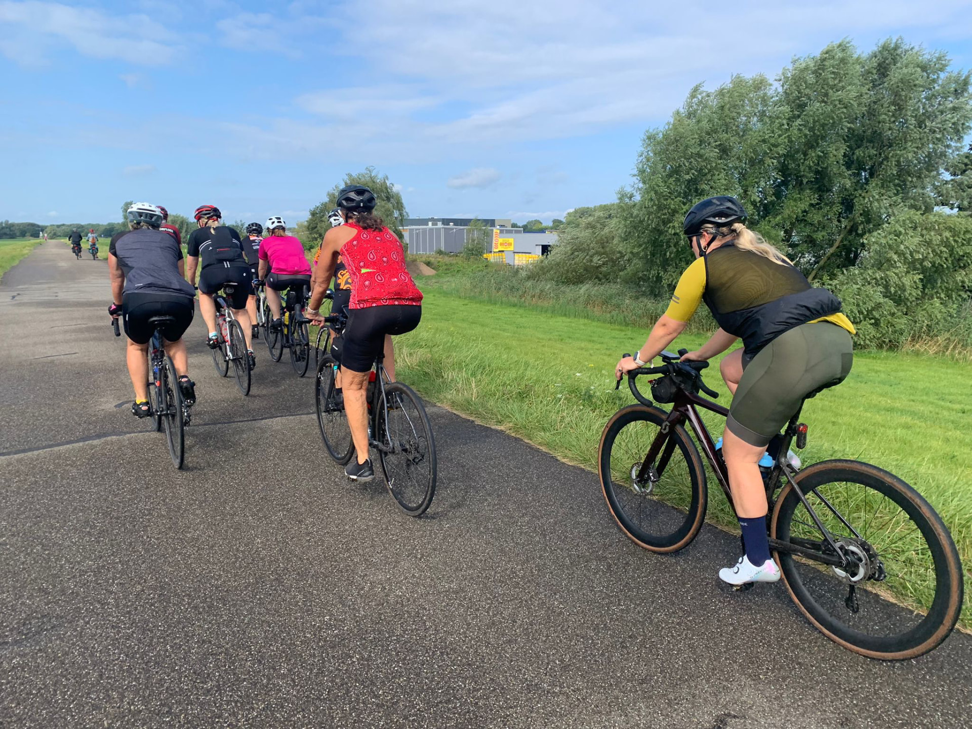 Sfeer van een eerdere Fietsvrouwen-rit: de groep fietst over een fietspad langs de dijk