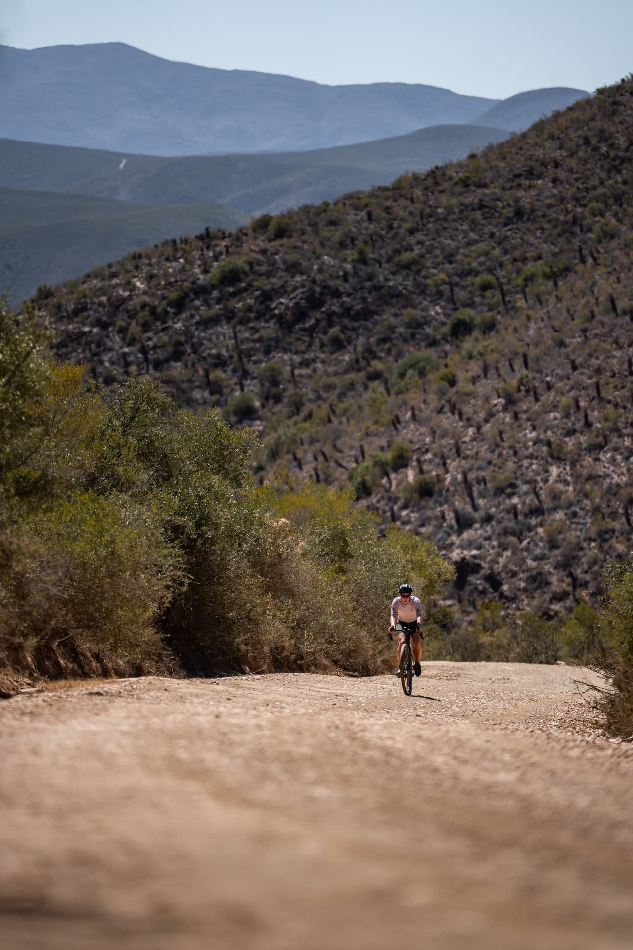 Cycling woman riding uphill through a vast mountain landscape