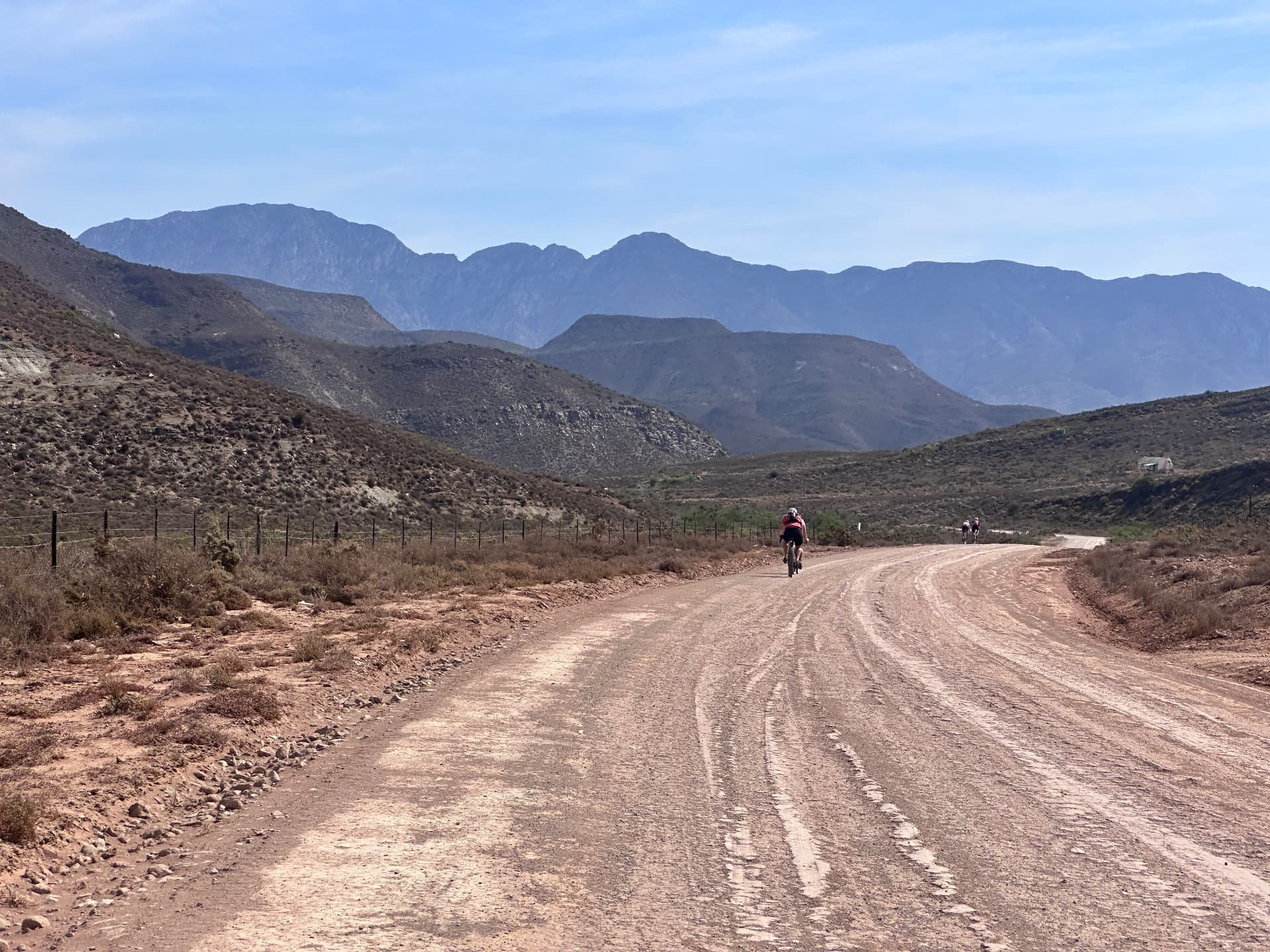 Cyclingwomen on their way on a wide gravel road through a mountain landscape