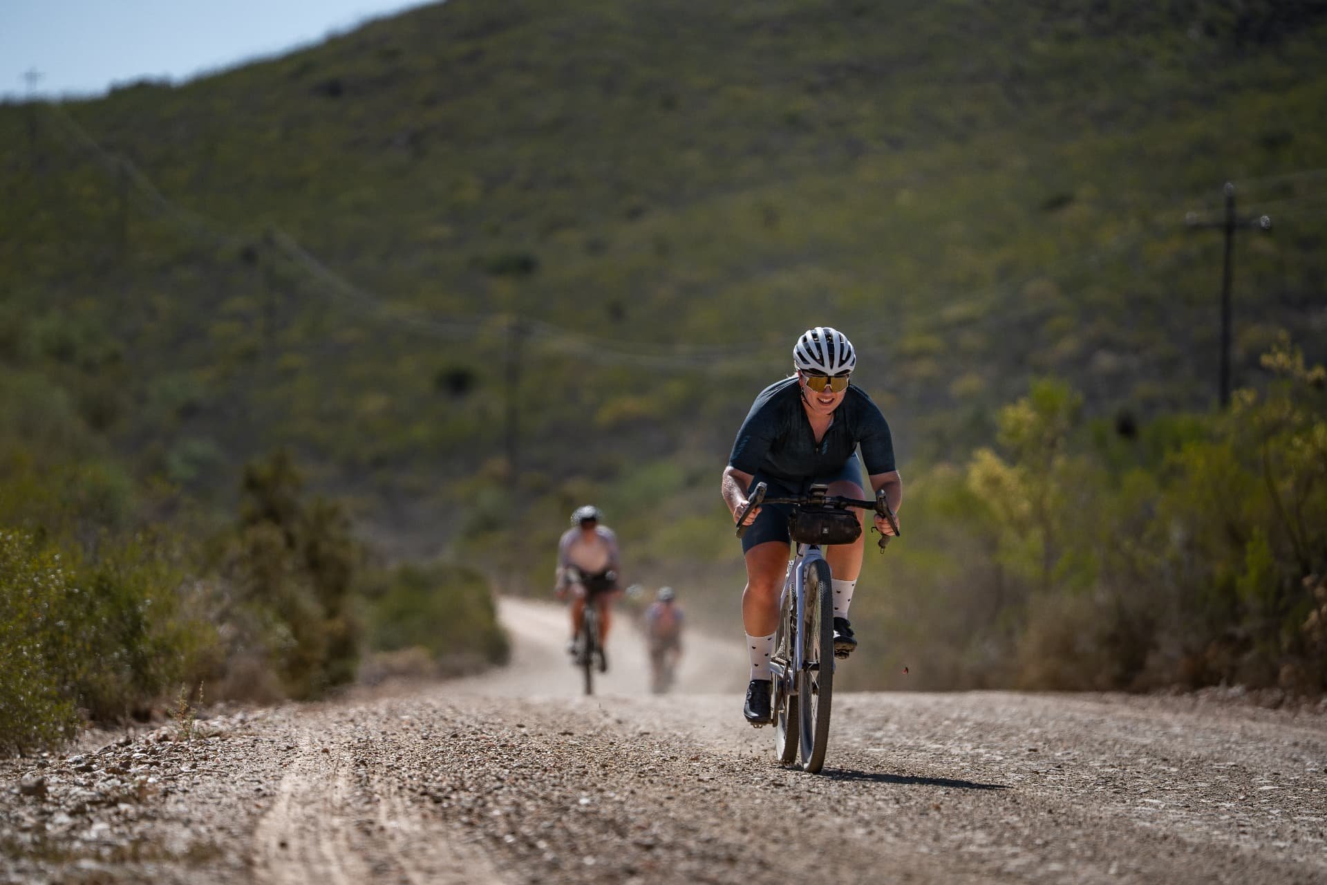 Cyclingwoman cycling uphill with a smile on a gravel road during a bike trip