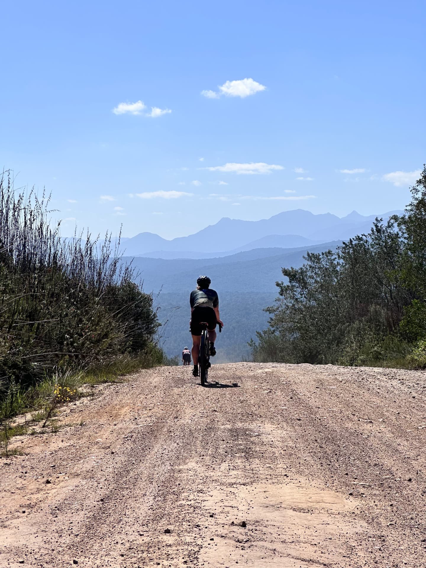 Cyclists on a gravel road with mountain views