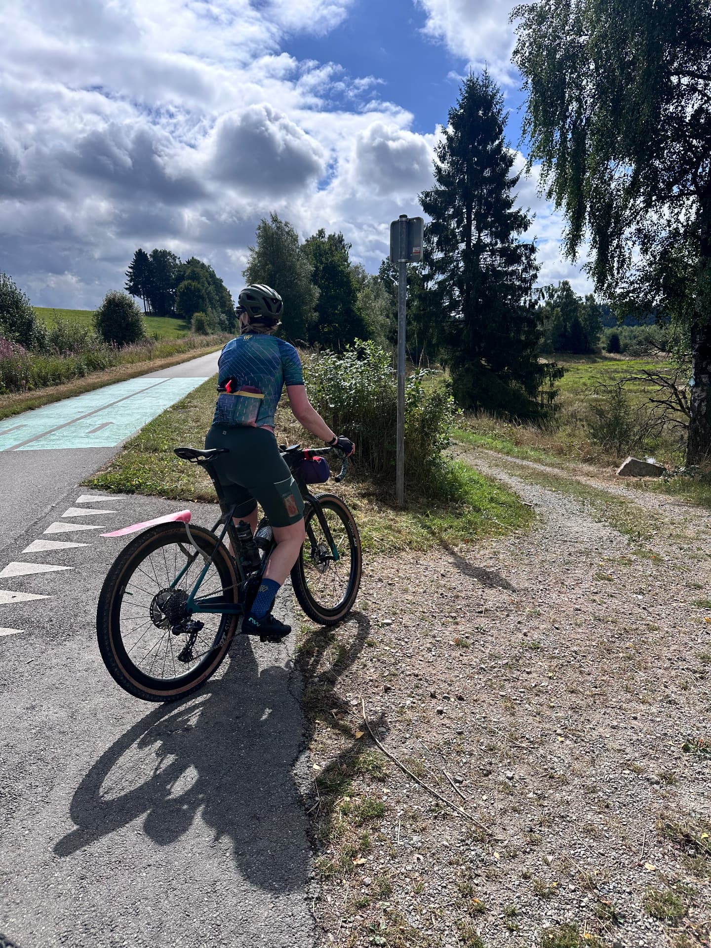 Sfeer van een eerdere Fietsvrouwen-rit in de Ardennen: een deelneemster fietst over een fietspad door het groen